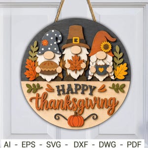 May include: A circular wooden door sign featuring three gnomes with autumn-themed accessories, including a pie, a maple leaf, and a mug. The sign displays the text "HAPPY thanksgiving" in layered wood, accented by a pumpkin and fall foliage.