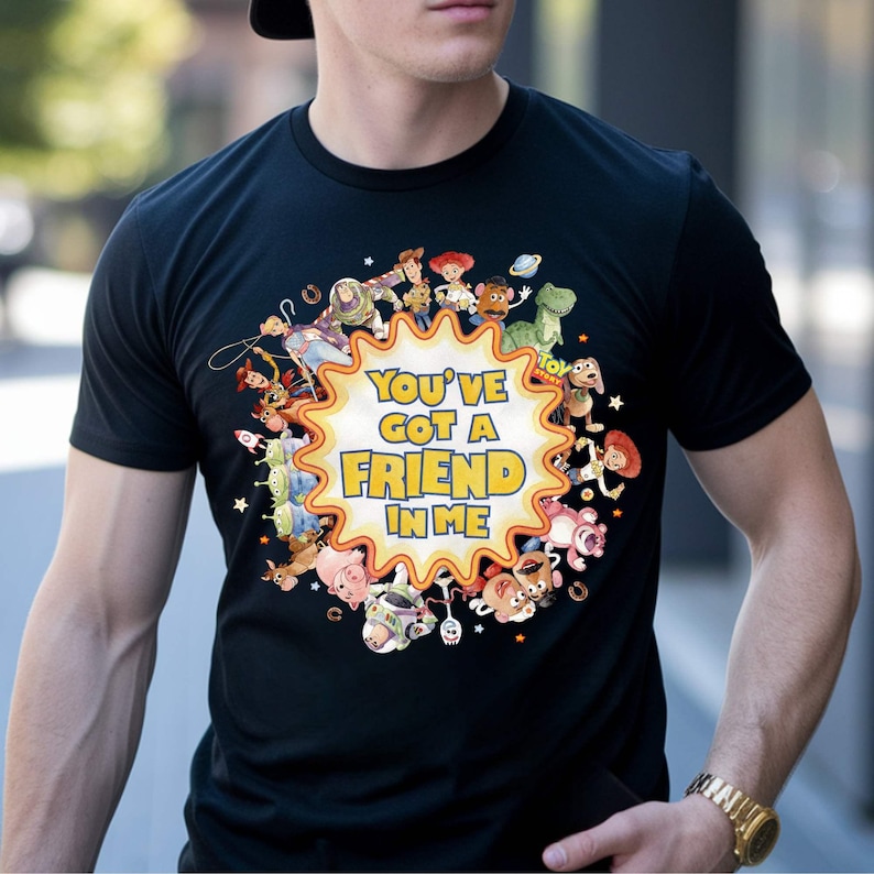 May include: Black t-shirt featuring a colorful graphic of characters from the movie Toy Story. The design includes the text "You've Got a Friend in Me" in yellow and orange. The shirt is a crew neck.