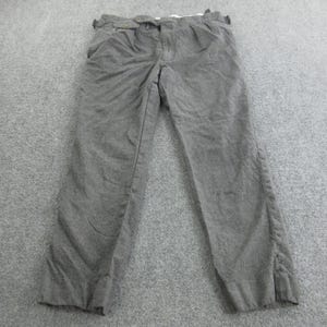 May include: Grey trousers with a button and zip fastening. The pants feature two front pockets and a straight leg cut. The fabric looks to be a medium-weight material, suitable for cooler weather. The trousers are laid flat on a grey surface.