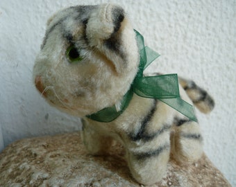 May include: A plush toy cat with black and white stripes, wearing a green ribbon around its neck.