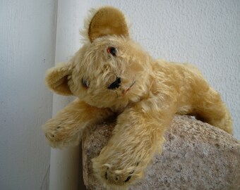 Vtg.golden mohair,unjointed teddy bear,lying position,glass eyes,threadbare/worn.
