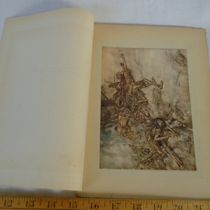 Op de afbeelding: Open boek met een gedetailleerde illustratie. Het kunstwerk toont figuren in een dynamische scène, met een gedempte kleurenpalet van bruin, beige en blauw. De linkerpagina is leeg.