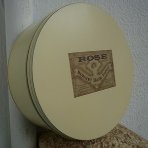Vintage,round,metal tin with lid,painted cream with Victorian style label & ribbon trim on lid-shabby chic.