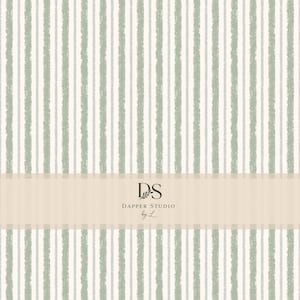 May include: A repeating pattern of vertical stripes in sage green and light gray on an off-white background. A horizontal beige band across the center features the black text DS DAPPER STUDIO by L with a small leaf graphic above the letters.