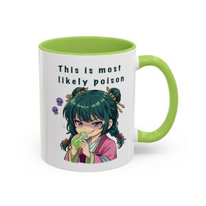May include: White ceramic mug with a green interior and handle. The mug features an anime-style illustration of a girl holding a potion, with the text "This is most likely poison".