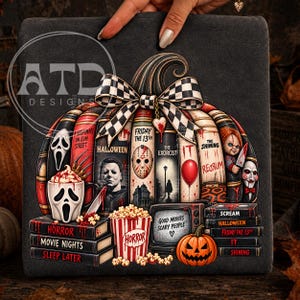 Könnte beinhalten: Eine dunkelgraue Stoffoberfläche mit einer Grafik eines Kürbisses, der aus Horrorfilm-Buchrücken besteht, darunter Titel wie Halloween, Friday the 13th und The Shining. Das Motiv enthält eine karierte Schleife, Popcorn und ein Fernsehgerät.
