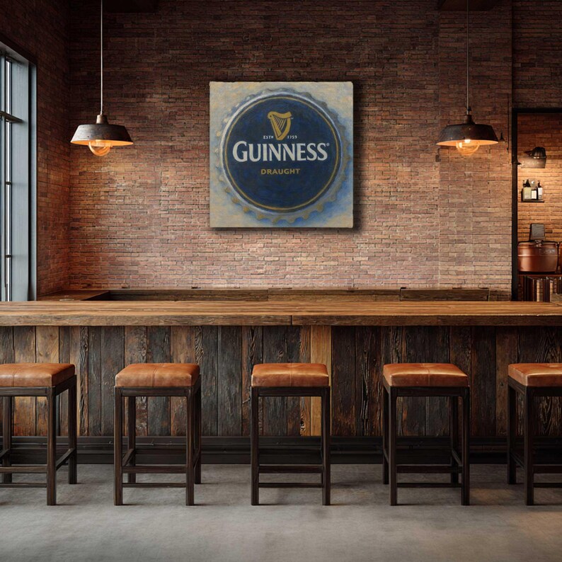 Op de afbeelding: Een barinterieur met een Guinness Draught-bord in blauw en goud op een bakstenen muur. De bar heeft een houten toonbank, leren krukken en hanglampen. Klassieke pub sfeer.