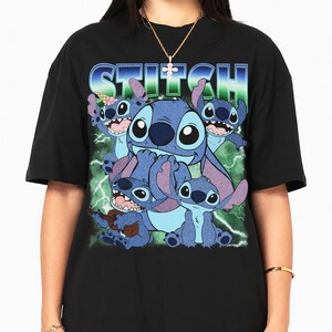 May include: A black short-sleeve t-shirt featuring a graphic print of the character Stitch in various poses. The word STITCH is printed in a blue and green gradient font at the top. The background of the graphic includes green lightning bolts.