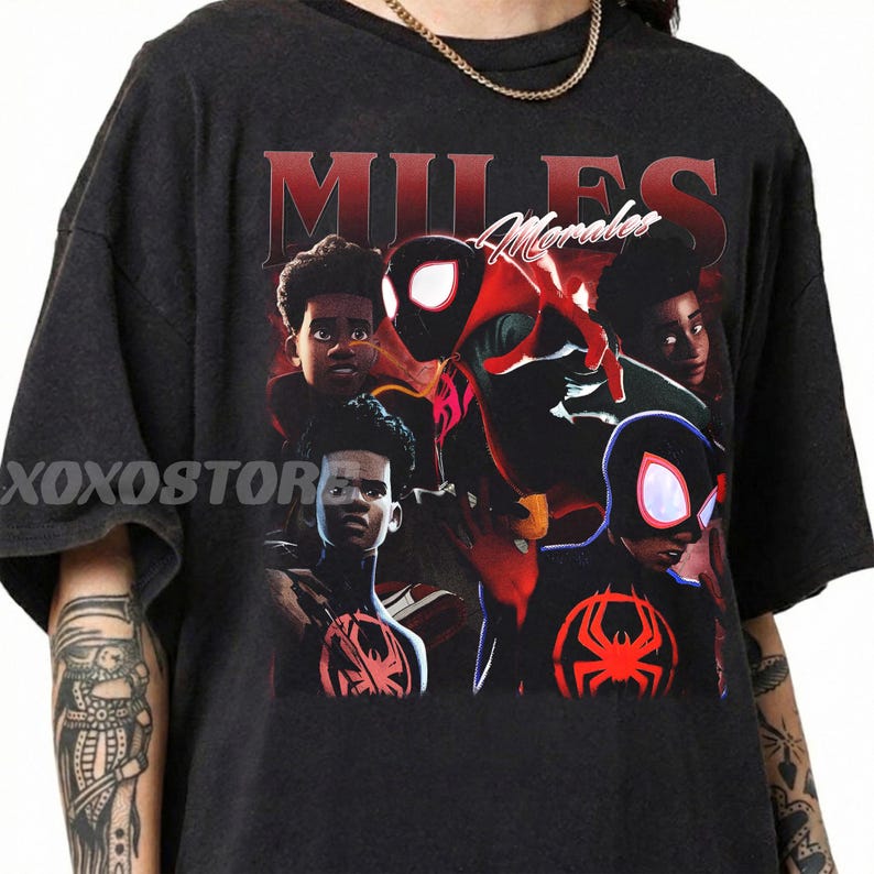 K&ouml;nnte beinhalten: Dunkelgraues T-Shirt mit einer Grafik von Miles Morales im Spider-Man-Anzug. Das Design enth&auml;lt den Namen "Miles Morales" in roter Schrift und mehrere Bilder der Figur. Das T-Shirt hat einen Rundhalsausschnitt und kurze &Auml;rmel.