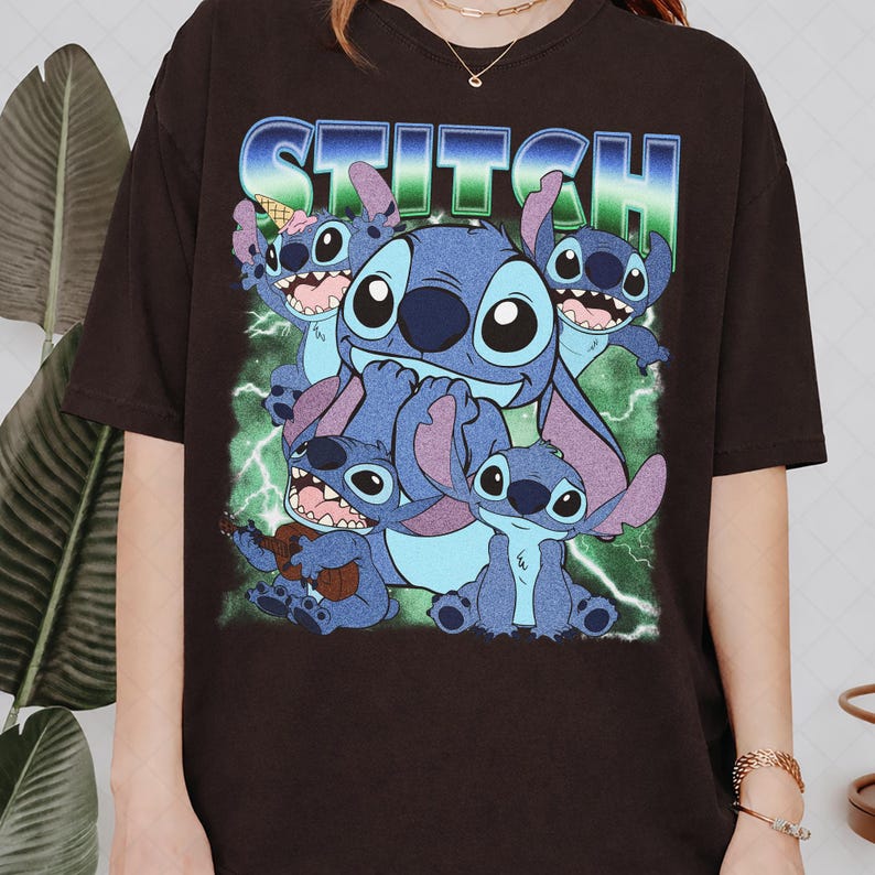 May include: A black short-sleeve t-shirt featuring a graphic print of the character Stitch in various poses. The design includes the text STITCH in a blue and green gradient font, set against a background of green lightning bolts and energy.