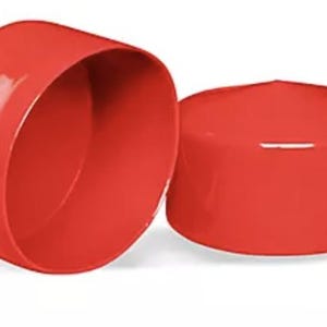 May include: Two bright red, cylindrical plastic end caps with a smooth, glossy finish. One cap is positioned to show its hollow interior, while the other is placed upside down to display its flat, solid top surface and rounded edges.