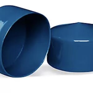 May include: Two glossy, deep blue cylindrical caps with smooth, rounded edges. One cap is positioned to show its hollow interior, while the other is placed beside it, displaying its solid, flat top surface and uniform, reflective finish.