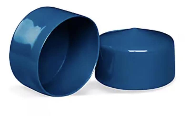 May include: Two glossy, deep blue cylindrical caps with smooth, rounded edges. One cap is positioned to show its hollow interior, while the other is placed beside it, displaying its solid, flat top surface and uniform, reflective finish.