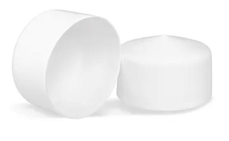 May include: Two white cylindrical end caps with a smooth, matte finish. One cap is positioned vertically, showing its hollow interior, while the other cap is placed horizontally next to it, displaying its solid, flat top surface and rounded edges.