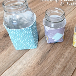 May include: Three glass jars with fabric covers. The covers display various patterns: blue polka dots, purple with shapes, and yellow floral. The text "Jar Cover Sewing Pattern & Tutorial" is at the top.
