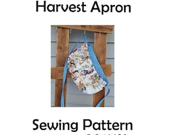 May include: A sewing pattern for a Harvest Apron, featuring a blue and white fabric with a harvest theme. The pattern is by Fantabul-O-Sew.