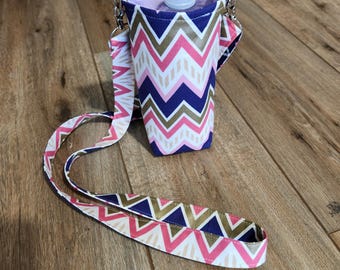 May include: A pink, gold, and navy blue water bottle holder with a chevron pattern. The holder has a long strap and is made of fabric.