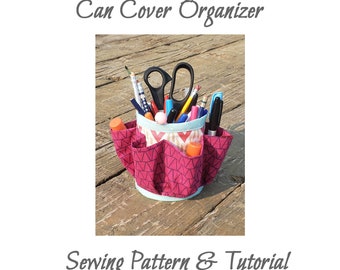 May include: A pink and blue fabric can cover organizer with multiple pockets. The organizer is filled with various school supplies, including pencils, pens, scissors, and glue sticks. The text "Can Cover Organizer" is at the top of the image and the text "Sewing Pattern & Tutorial" is at the bottom of the image.