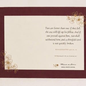 Puede incluir: Una tarjeta rectangular con un borde burdeos oscuro y un centro color crema. El texto dice: Two are better than one; if they fall, the one will lift up his fellow. And if one prevail against him, two shall withstand him; and a threefold cord is not quickly broken. ECCLESIASTES 4:9-10, 12. A blessing for the two becoming one. Maison de Lettre WORDS WORTH KEEPING. Dibujos lineales florales dorados decoran las esquinas.