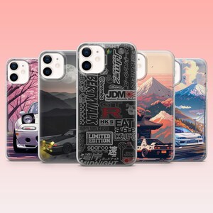 Puede incluir: Una colección de cinco fundas para teléfonos con diseños temáticos de coches. Las fundas presentan ilustraciones de coches, paisajes y texto japonés. La paleta de colores incluye tonos de rosa, negro, blanco y rojo.