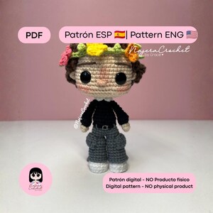 Puede incluir: Muñeca de ganchillo con corona de flores, camisa negra y pantalón gris. La muñeca tiene ojos negros grandes y un tono de piel neutro. El texto en la imagen dice "Patrón ESP | Pattern ENG" y "Digital pattern - NO physical product."