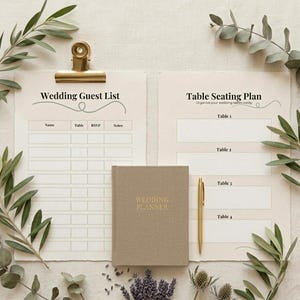 Può includere: Un set di pianificazione del matrimonio con una lista degli invitati e un piano dei tavoli, tenuti insieme da una clip dorata. Sono inclusi anche un libro di pianificazione del matrimonio beige e una penna dorata. Il verde e i rametti di lavanda circondano la cancelleria.