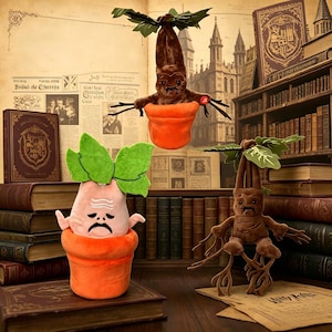 Pode incluir: Figuras de Mandrágora de pelúcia em vasos laranja com folhas verdes. As Mandrágoras têm corpos castanhos e estão colocadas em um fundo de livros e pergaminho. As figuras têm diferentes expressões faciais.
