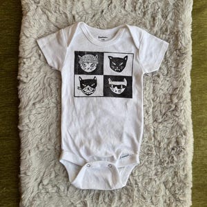 May include: A white ceramic mug with a black handle and the text "But First, Coffee" in a black, handwritten-style font. The mug is on a white surface.