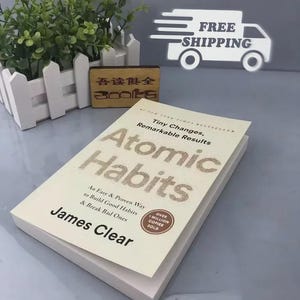 May include: A copy of "Atomic Habits" by James Clear, a New York Times bestseller. The book has a cream-colored cover with the title in large, textured letters. The cover also features the text "Tiny Changes, Remarkable Results."