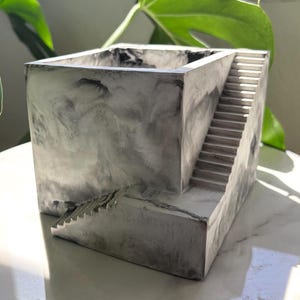 Puede incluir: Un juego de tres tazas de cerámica con un acabado mate moteado. Cada taza presenta un color diferente: azul claro, crema y gris. Las tazas tienen un diseño simple y moderno y un asa cómoda.