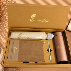 May include: A tan gift box containing a brown notebook with a textured cover, a matching metallic pen, a cylindrical vacuum-insulated bottle, and a white cloth pouch. Each item features the gold-colored Beawiaglow logo and leaf icon.