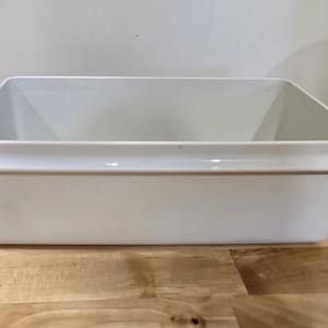 May include: A white plastic storage container with a smooth, rectangular shape. The container has a raised lip around the top edge.