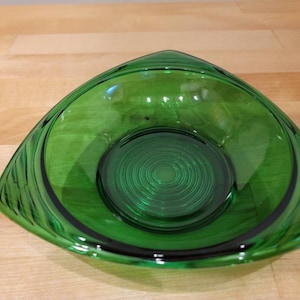 Op de afbeelding: Een groene glazen kom met een swirl-patroon aan de binnenkant. De kom is driehoekig en heeft een brede rand.