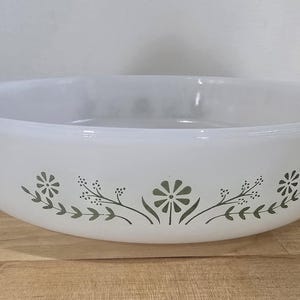 Peut inclure: Bol à servir rond blanc avec un motif floral vert. Le bol a un large bord et est décoré de fleurs et de feuilles stylisées. Un article de cuisine vintage.