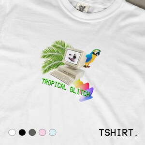 May include: White t-shirt with a graphic design featuring a vintage computer with a dog's face on the screen, a parrot, and palm leaves. The text "TROPICAL GLITCH" is in green, and the word "TSHIRT" is in black.