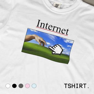 May include: White t-shirt featuring the word "Internet" above a graphic of a hand reaching towards a computer cursor over a green field and blue sky. The word "TSHIRT" is printed at the bottom.