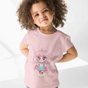 May include: A light pink t-shirt featuring a cartoon illustration of a girl with pink hair, a blue dress, and a pink cape. The girl is standing on a cloud. The child is wearing blue jeans.