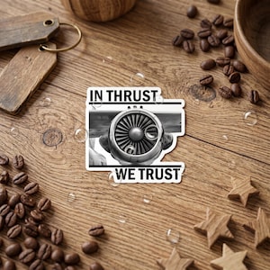 May include: A rectangular sticker featuring a black and white photograph of a jet engine turbine. The text IN THRUST is printed in black above the engine, and the text WE TRUST is printed in black below the engine on a white background.