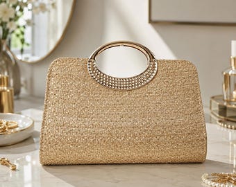 May include: A structured beige woven straw handbag featuring a semi-circular gold-tone metal handle. The handle is embellished with a series of small, raised circular studs along the lower edge, providing a metallic contrast to the textured straw body.
