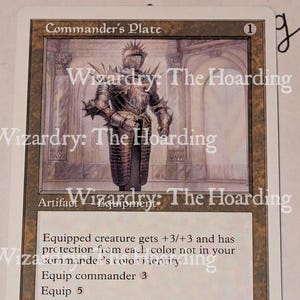 May include: A Commander's Plate trading card featuring a suit of spiked metal armor in a stone hall. The text reads Commander's Plate, Artifact Equipment, Equipped creature gets +3/+3 and has protection from each color not in your commander's color identity, Equip commander 3, Equip 5, and Illus. Volkan Baga.