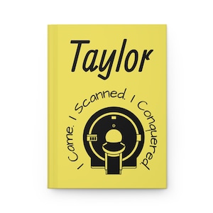Op de afbeelding: Een gele notitieboek met de naam "Taylor" in zwart schrift. Daaronder een zwart-wit illustratie van een medische scanner. De tekst "I came. I scanned. I conquered." staat rond de scanner.