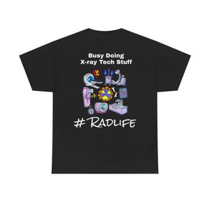 Op de afbeelding: Zwart t-shirt met een kleurrijke afbeelding van röntgentechnologie-apparatuur en de tekst "Busy Doing X-ray Tech Stuff" en "#RADLIFE". Het ontwerp bevat afbeeldingen van medische scanners en stralingssymbolen.