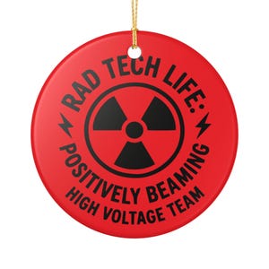 Puede incluir: Adorno redondo rojo con el texto negro "RAD TECH LIFE: POSITIVELY BEAMING HIGH VOLTAGE TEAM". Un símbolo de radiación negro está en el centro. Una cuerda dorada está unida para colgar.