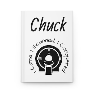 Op de afbeelding: Wit notitieboek met de naam "Chuck" in zwart schrift. Daaronder een zwart-wit illustratie van een medische scanner. De tekst "Came. I Scanned. I Conquered." is rond de scanner gedrukt.