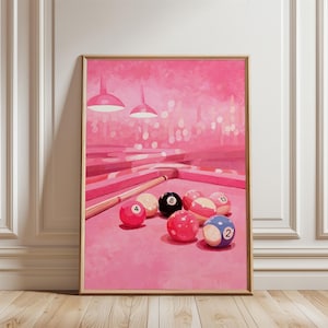 May include: A rectangular wall art print featuring a monochromatic pink-toned illustration of a pool table. The scene includes a wooden cue stick and several numbered billiard balls, including the black eight ball, resting on the pink felt surface.