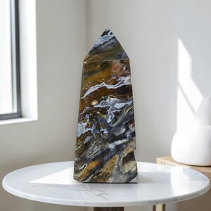 Polished ocean jasper crystal tower displayed on white marble table near window