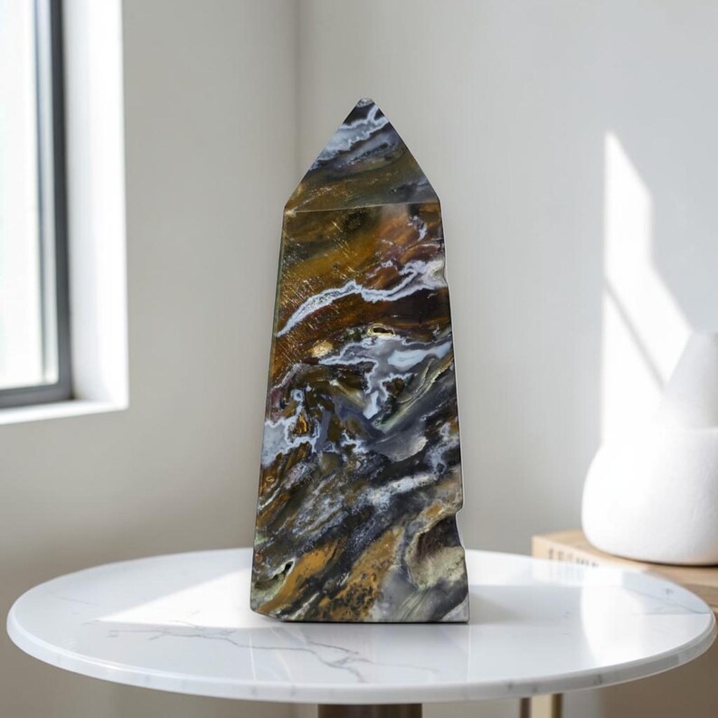 Polished ocean jasper crystal tower displayed on white marble table near window