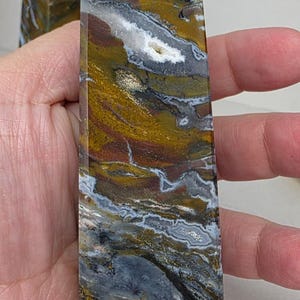 Ocean jasper tower with swirling natural patterns held in hand for scale