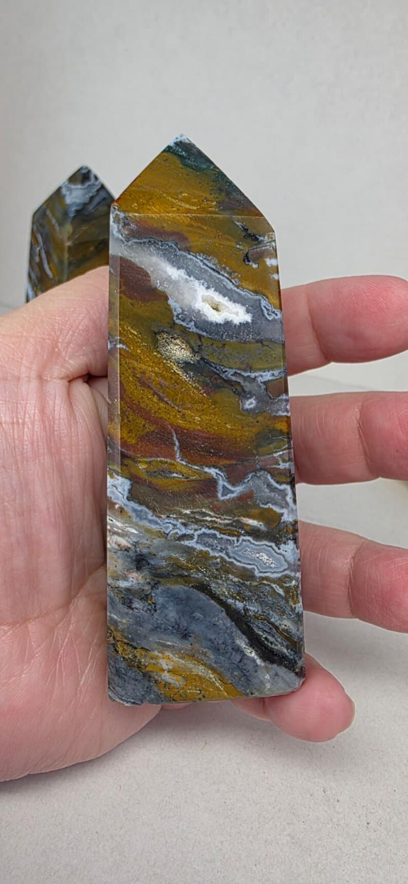 Ocean jasper tower with swirling natural patterns held in hand for scale