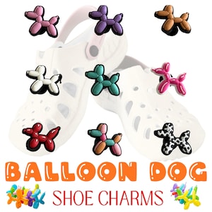 May include: A collection of colorful balloon dog shoe charms in various colors, including pink, purple, brown, white, teal, red, and a black and white spotted design. The charms are displayed on white shoes, with the words "BALLOON DOG SHOE CHARMS" in orange and red.